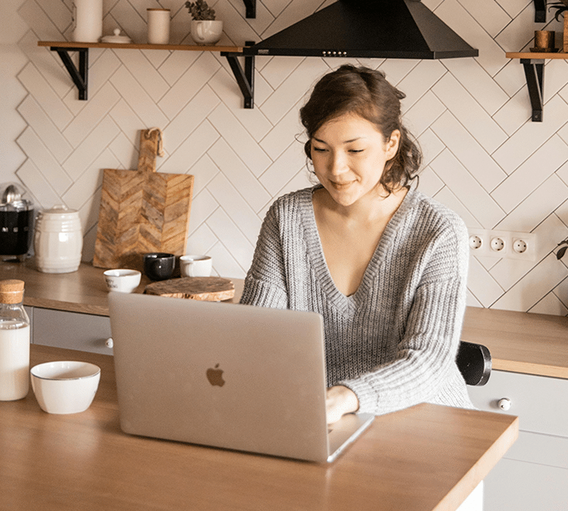 Person working on laptop in kitchen.