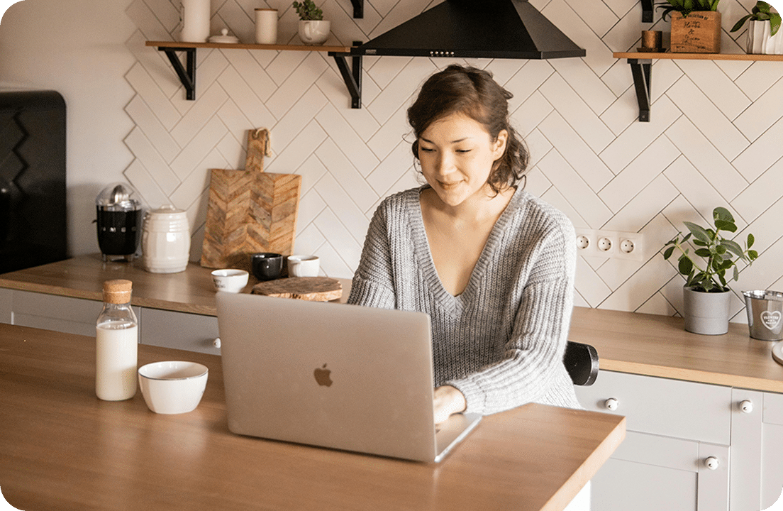 Person working on laptop in kitchen.